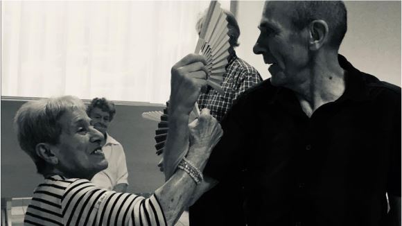 Image noir et blanc de deux séniors apprenants à danser lors d'un cours leur étant destiné de la Compagnie Mouvementé Danse.